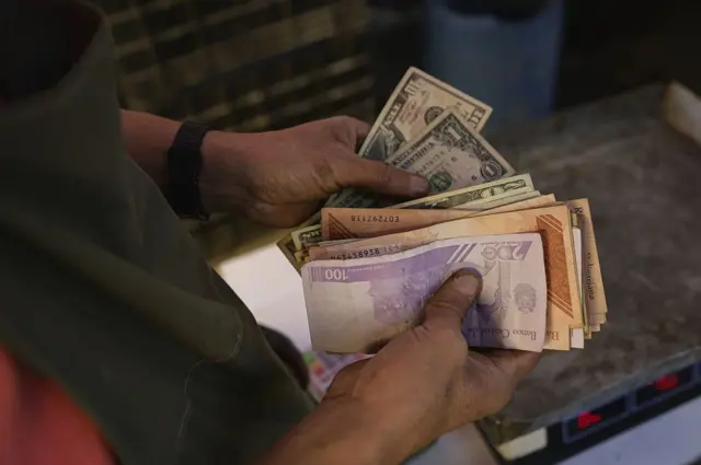 Un comerciante cuenta dólares y bolívares