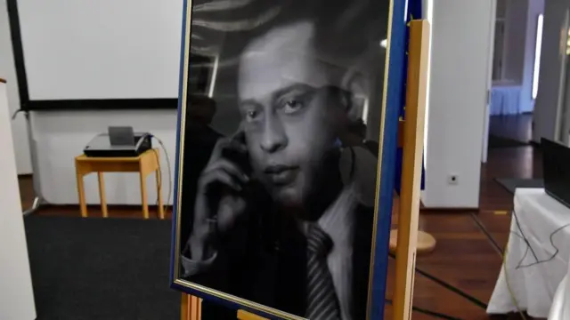 Un retrato enmarcado en blanco y negro del médico egipcio Mohamed Helmy con camisa a rayas y corbata.