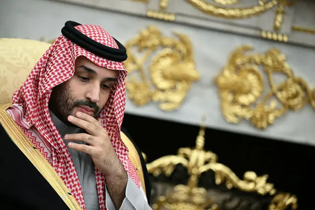El príncipe heredero saudita Mohamed bin Salman, a la izquierda de la foto, mira hacia abajo y se lleva la mano a la barbilla.