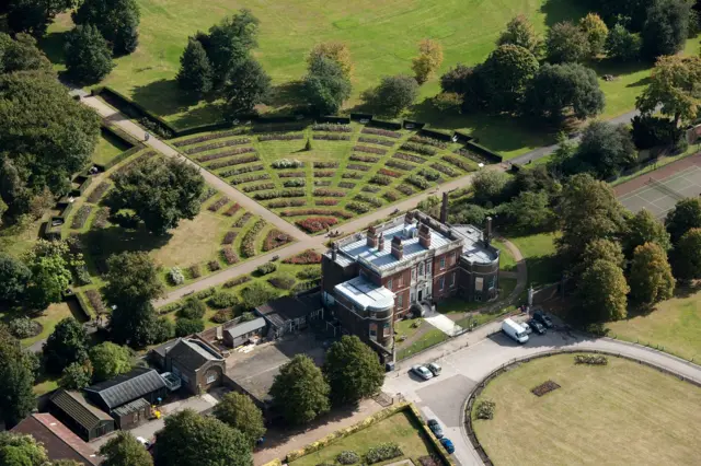 Una toma aérea de una mansión georgiana en el borde de Greenwich Park, que muestra césped y un estacionamiento.
