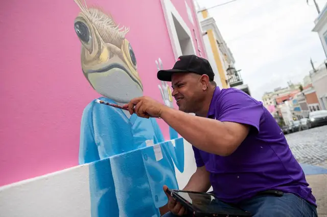 Un artista pintando un mural de un sapo concho.