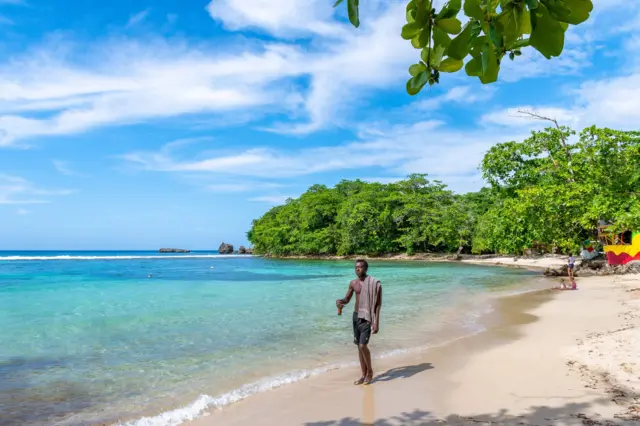 Un jamaiquino pasea por una playa.