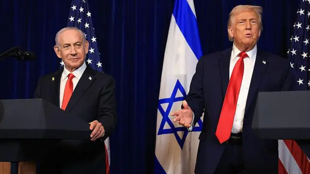 Netanyahu, sonriente, con el pelo gris y vestido con traje, en un atril durante una rueda de prensa en Mar-a-Lago en diciembre con Trump, que tiene el pelo rubio peinado hacia atrás y también viste traje.