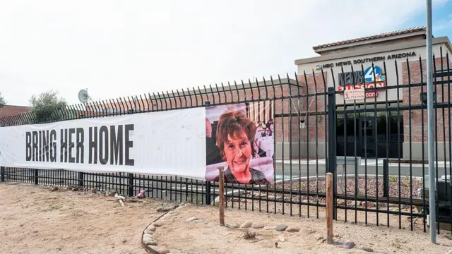 Una pancarta colgada en la puerta exterior de una filial local de NBC muestra una foto de Nancy Guthrie y dice: Tráiganla a casa.