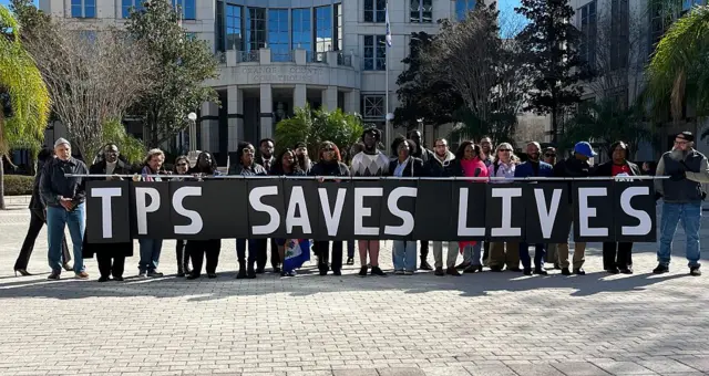 El jueves 29 de enero de 2026, frente al Palacio de Justicia del Condado de Orange, Florida. personas cargan un lienzo que dice "EL TPS salva vidas"