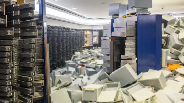 Una imagen que muestra un desorden en una bóveda de un banco con archivos por todo el suelo.