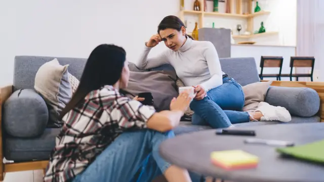 Dos mujeres conversando en el living de una casa