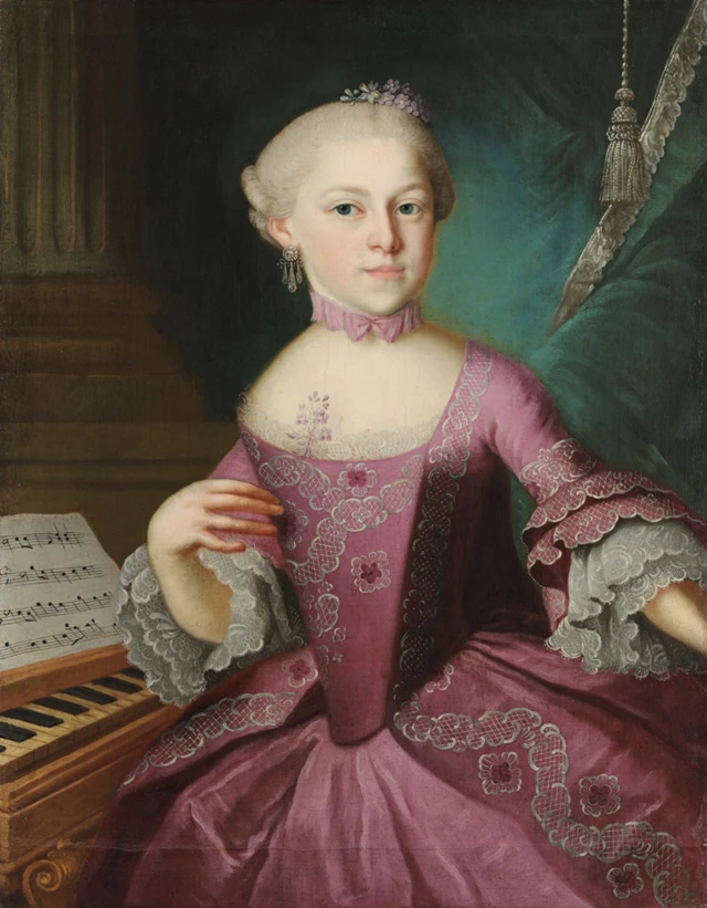 Nannerl con un elegante vestido rosado con encajes blancos al lado de un piano y unas partituras.
