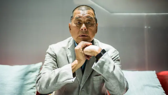 Jimmy Lai posa durante una entrevista con AFP en las oficinas de Next Digital en Hong Kong. Lleva un traje color crema y un reloj negro en la muñeca.