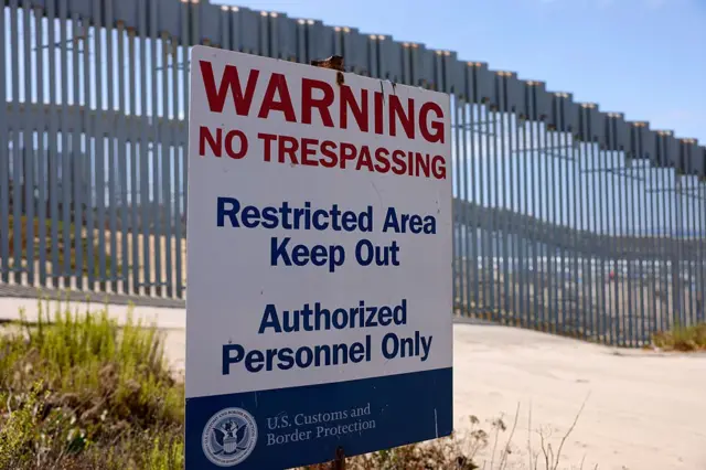 Un cartel de la Oficina de Aduanas y Protección Fronteriza de Estados Unidos (CBP) se puede ver en el Parque Estatal Border Field, con el muro fronterizo entre Estados Unidos y México de fondo.