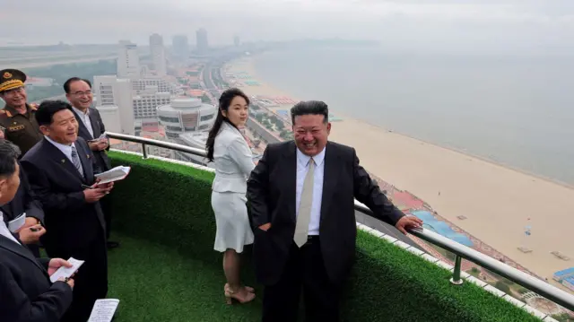 El líder norcoreano Kim Jong-un y su hija Kim Ju-ae se encuentran en un balcón frente a la playa durante una ceremonia para celebrar la finalización de la Zona Turística Costera Wonsan Kalma, en Wonsan, Corea del Norte, el 24 de junio de 2025.