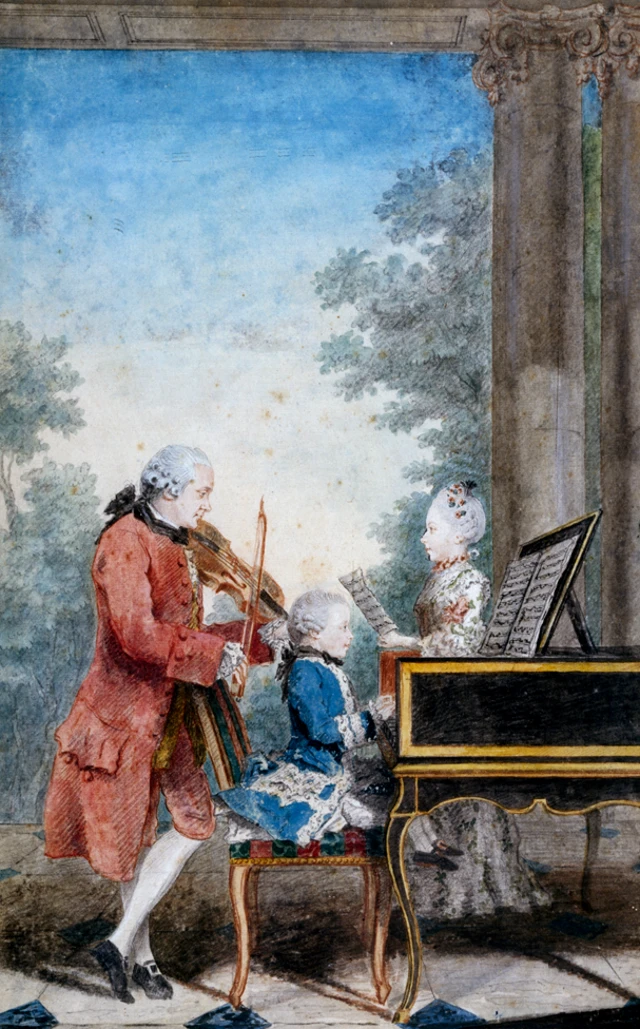 Leopold, con una chaqueta larga roja, toca el violín parado, mientras que Wolfgang, con una chaqueta azul, toca el piano sentado y Nannerl, con un vestido blanco largo, lee una partitura estando parada.