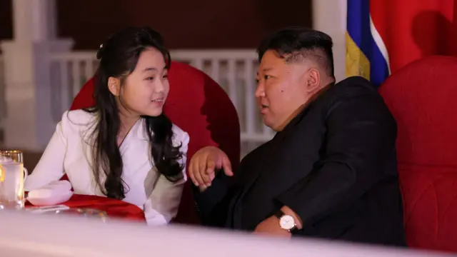 El líder norcoreano Kim Jong-un y su hija Kim Ju-ae conversan mientras asisten a la ceremonia de lanzamiento de un buque de guerra que resultó dañado en su primer intento de lanzamiento, en Rajin, Corea del Norte, el 12 de junio de 2025.