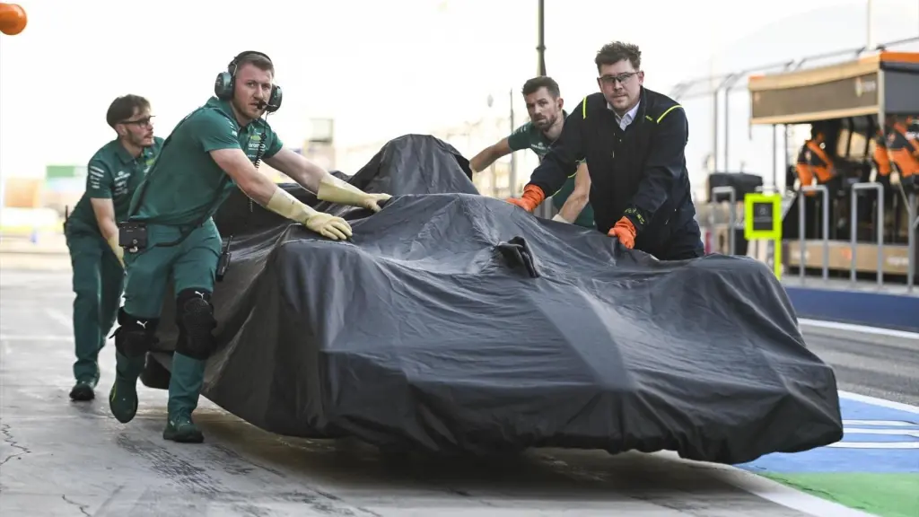Los mecánicos de Aston Martin llevan al garaje el ARM26 de Fernando Alonso