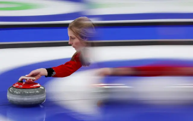 La suiza Briar Schwaller-Huerlimann en una prueba de curling, con su cuerpo difuminado por una larga exposición de la cámara, en Milán-Cortina 2026