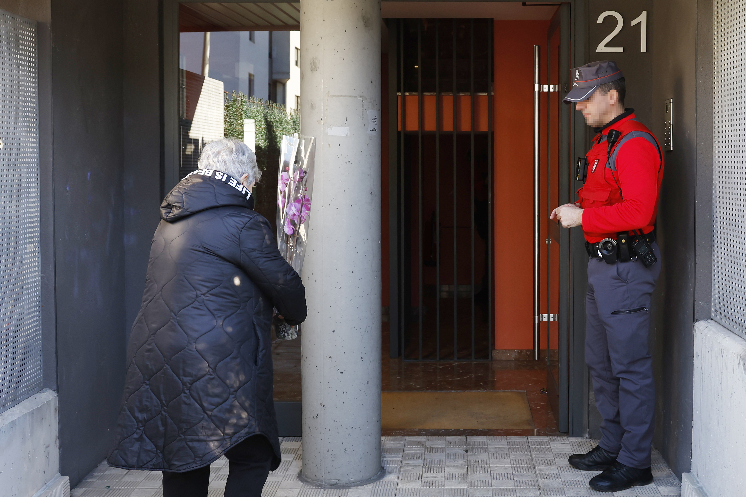 Una mujer deja una planta en el portal de la vivienda de Sarriguren donde una mujer fue asesinada este viernes.