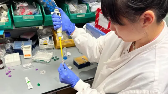 La profesora Liu mientras coloca la muestra de sangre del periodista en un recipiente para ser analizada.