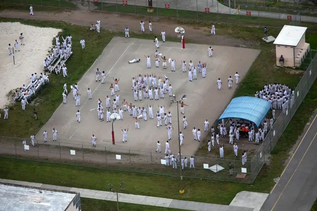 Migrantes vestidos de blanco en el patio de un centro de detención en Florida.