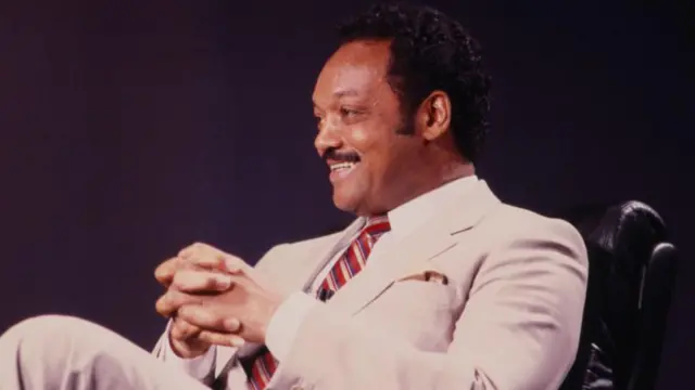 Jesse Jackson es fotografiado sonriendo a una persona que no se ve.