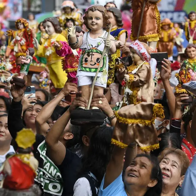 Personas en Manila sosteniendo figuras del Santo Niño Jesús, un ícono introducido en Filipinas por Magallanes