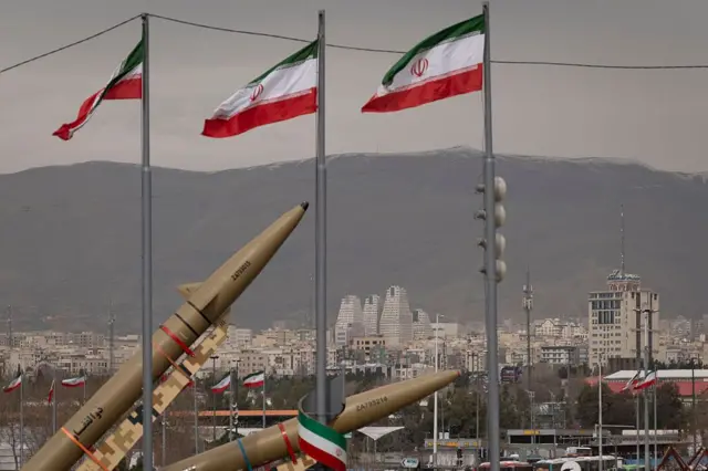 Entre banderas iraníes se encuentran dos misiles balísticos fabricados en Irán, con Teherán visible al fondo.