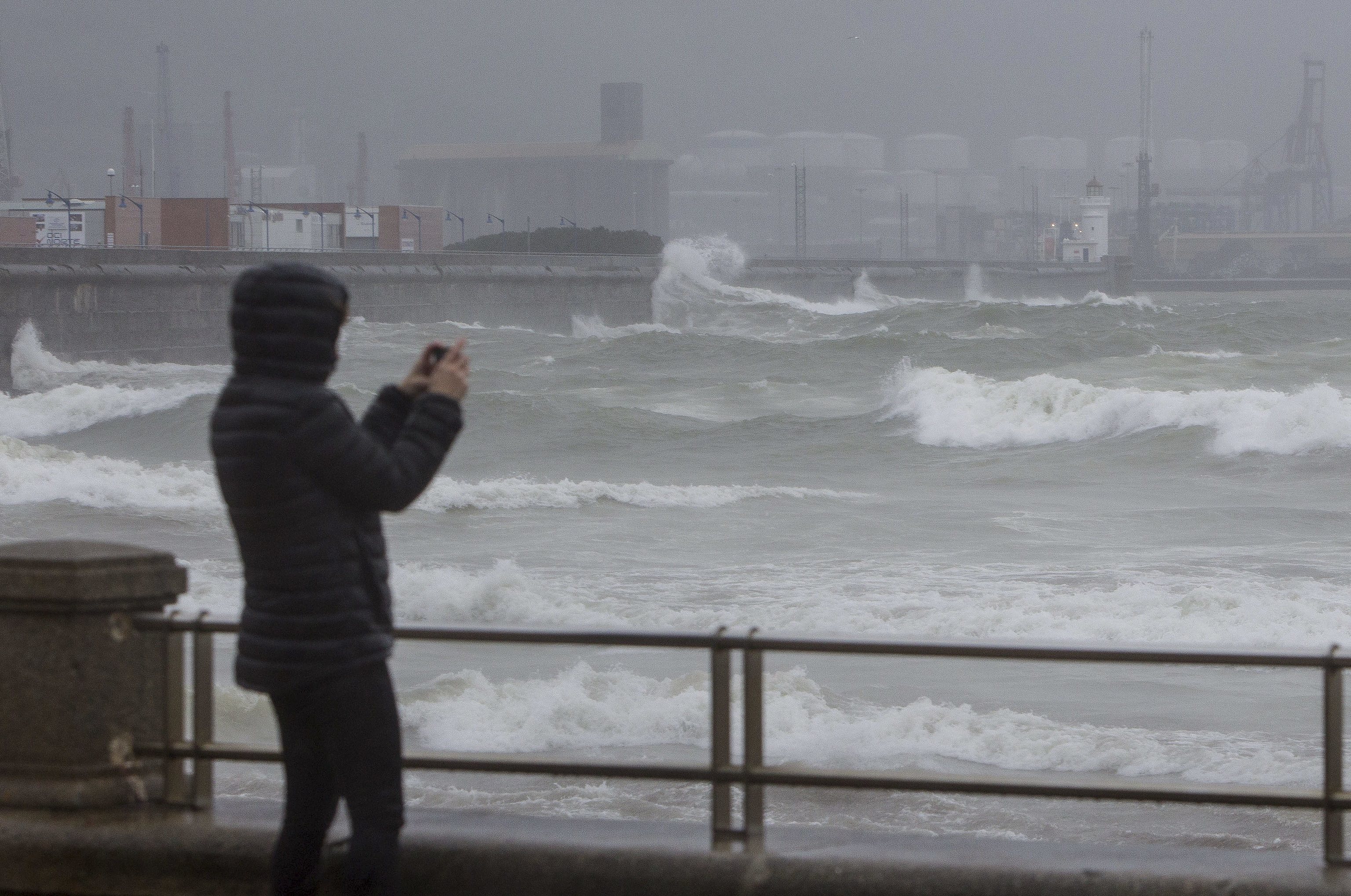 Una mujer hace fotografías a un mar embravecido por el temporal en Bilbao.