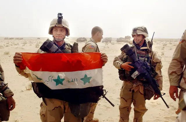 Soldados de EEUU con una bandera iraquí capturada.