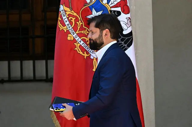 Boric camina delante de la bandera de Chile