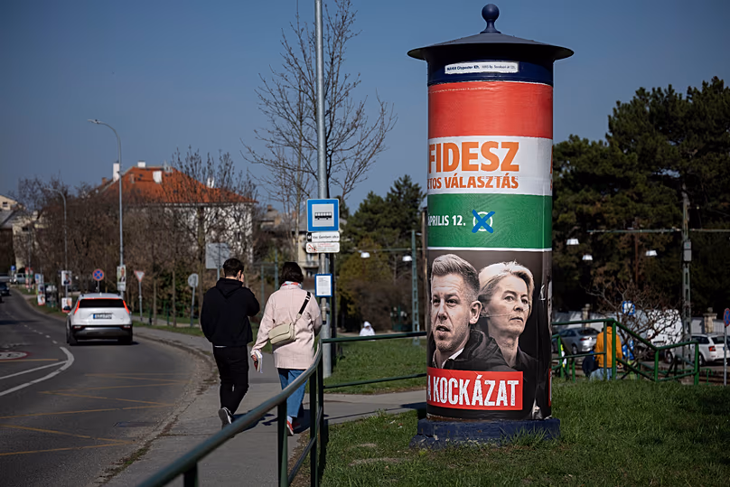 People walk next to a campaign poster which reads, "They're a risk. Fidesz is the safe choice" in Budapest, 14 March, 2026