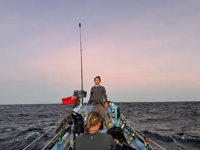 Dos de los hermanos en el bote, con un precioso atardecer rosa a sus espaldas.