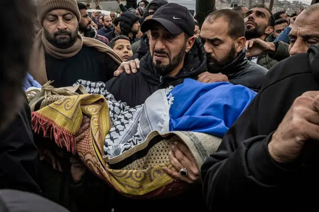 Un hombre carga el cuerpo de Mohammed Bani Odeh, de cinco años, durante el funeral de cuatro miembros de la misma familia muerta en manos de las fuerzas israelíes.