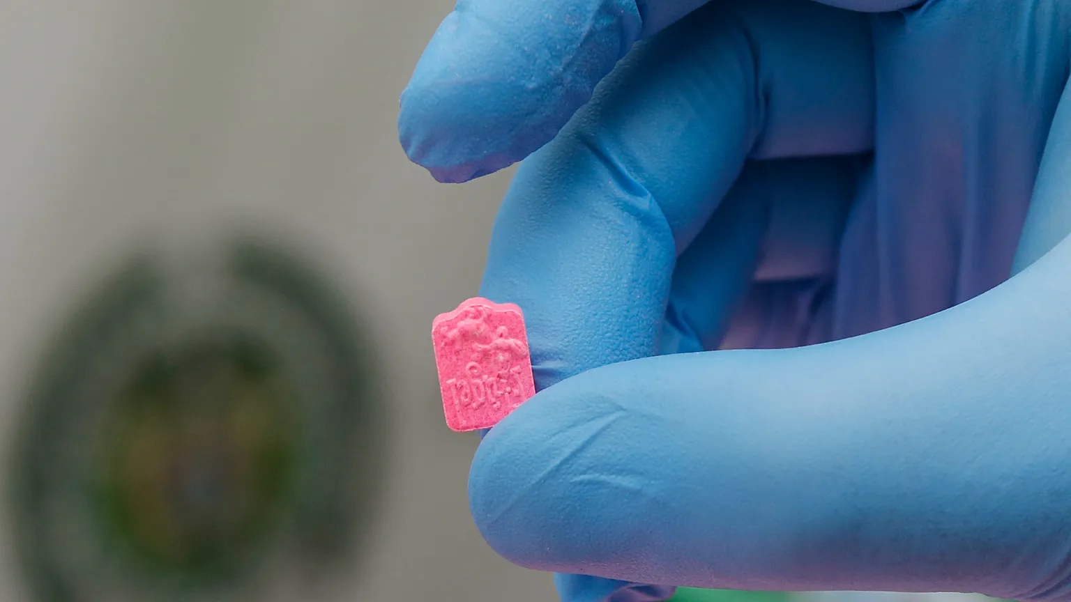 A police officer holds a single MDMA tablet, also known as ecstasy, during a media presentation at the El Dorado Airport, in Bogota, Colombia, Thursday, June 22, 2017.