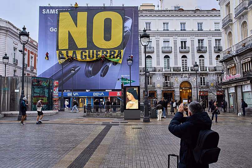Greenpeace activists hang a banner reading in Spanish, "Not to war" in downtown Madrid, Spain, Tuesday, March 10, 2026.