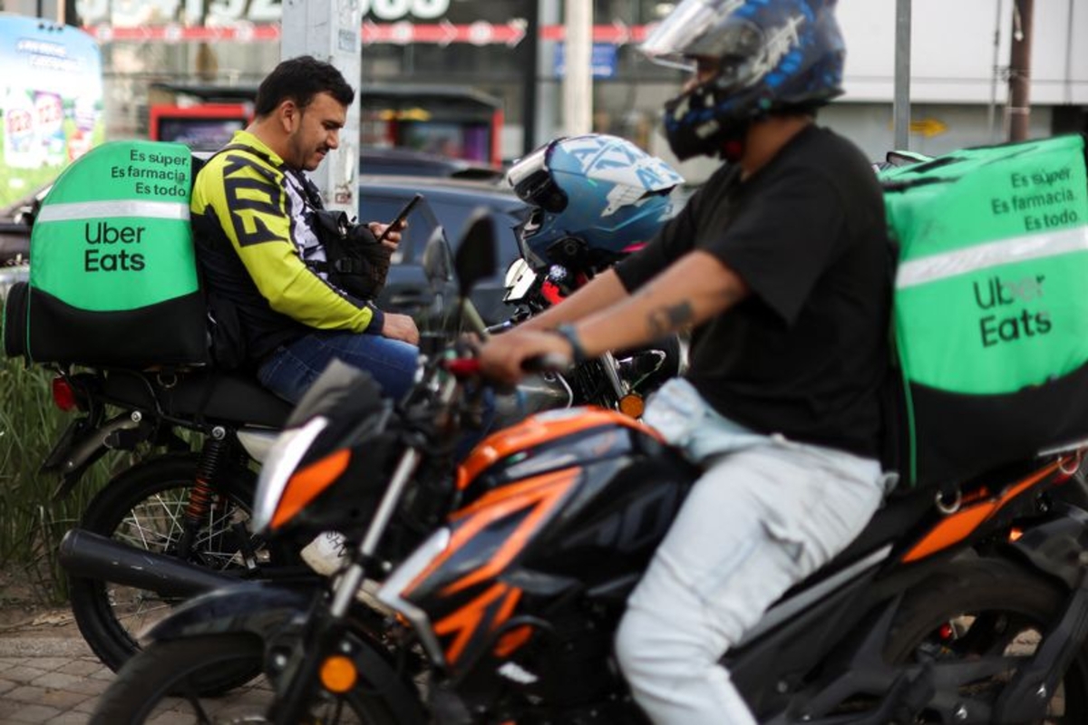 Los conductores de entrega de Uber Eats descansan mientras esperan pedidos de comida. (REUTERS/Gustavo Graf)