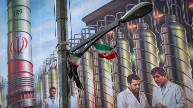 Un cartel en Teherán muestra equipos de enriquecimiento de uranio y científicos iraníes muertos en ataques israelíes en junio de 2025.