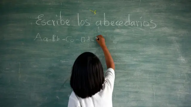 Niña escribe en una pizarra palabras en español