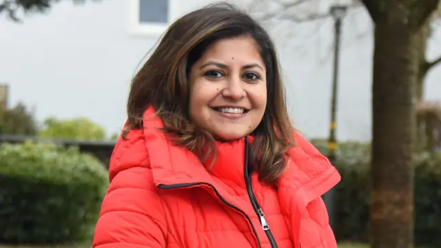 Aditi Banerjee, de la agencia de empleo india Magic Billion. Una mujer de pelo castaño, vestida con una gruesa chaqueta roja 
