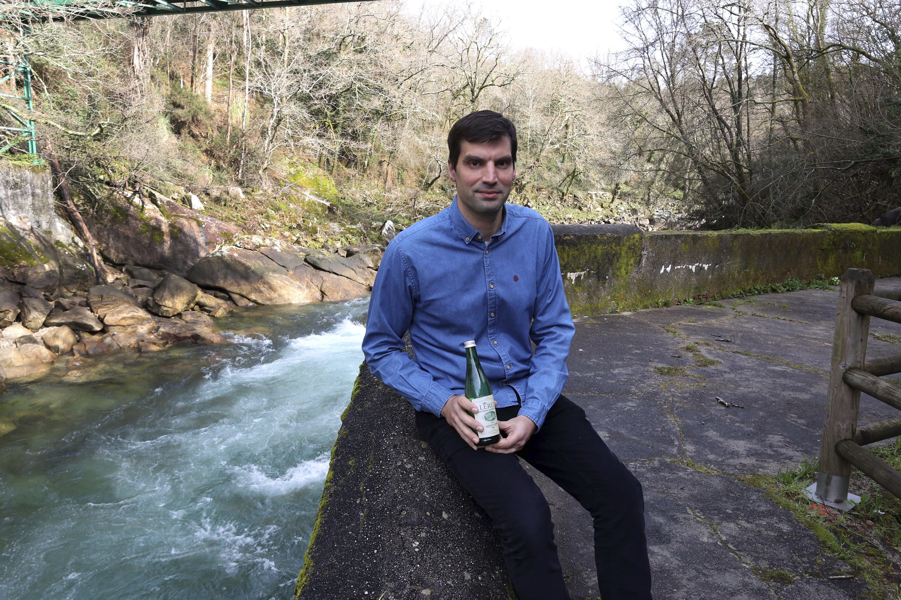 Carlos Fontán muestra una de las botellas en las inmediaciones de la antigua fuente de la que salía el agua