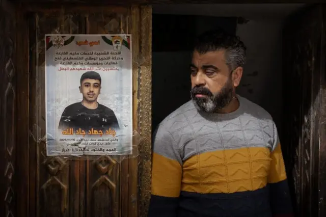 El padre de Jad Jadallah está de pie junto a un cartel conmemorativo por la muerte de su hijo de 14 años