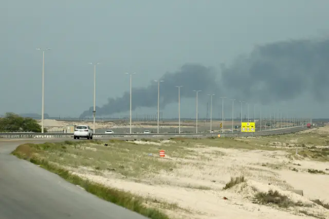 Los vehículos circulan por una carretera mientras el humo se eleva desde la refinería de petróleo de Ras Tanura, propiedad de Saudi Aramco, tras un presunto ataque con drones iraníes.