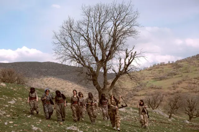 Un grupo de mujeres combatientes camina colina abajo después de un ejercicio militar.