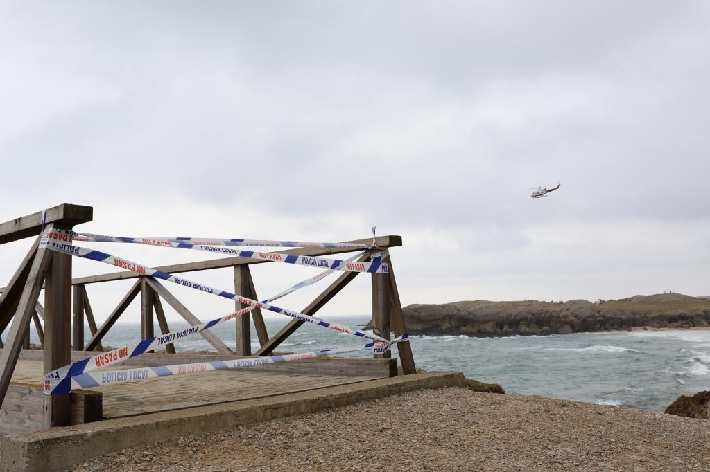 Un helicóptero sobrevuela (al fondo) la zona donde se produjo la rotura de la pasarela, ahora precintada, en Santander.