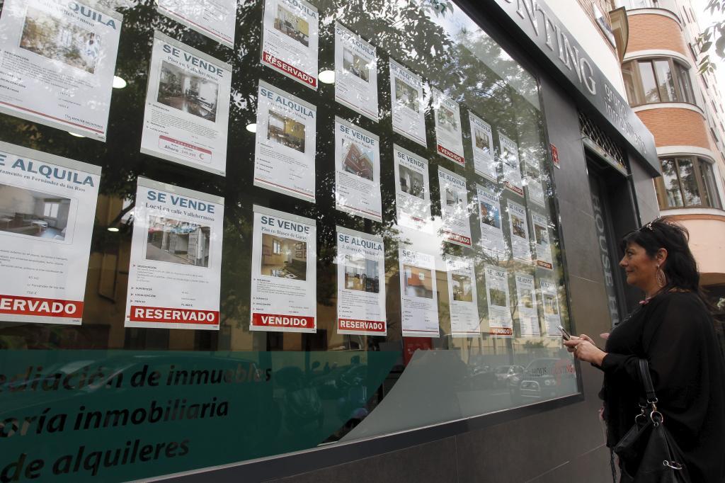 Una mujer mira el escaparate de una inmobiliaria.