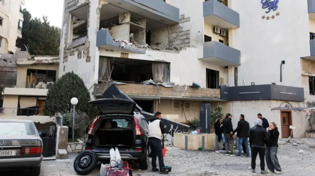Varias personas junto a un edificio afectado por los ataques israelíes en Beirut.