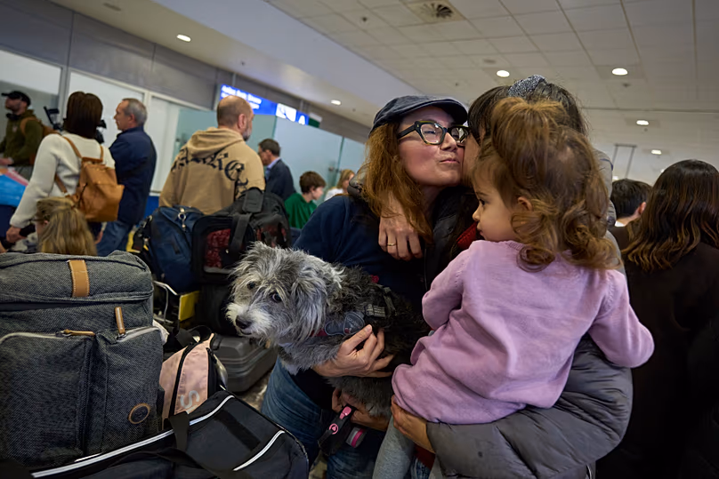 A repatriated Greek woman with her dog hugs relatives during their arrival at Athens International Airport Eleftherios Venizelos after being evacuated from Abu Dhabi.