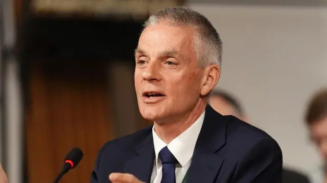 El director general de la BBC Tim Davie con un saco y corbata habla ante un micrófono