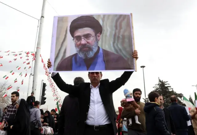 Un hombre sostiene un cartel con la foto de Mojtaba Jamenei