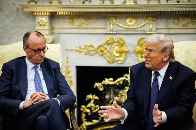 Friedrich Merz, canciller de Alemania, a la izquierda, y el presidente de los Estados Unidos, Donald Trump, durante una reunión en la Oficina Oval. Ambos están sentados, vestidos con traje de chaqueta y corbata. El fondo es una decorazción blanca y llena de detalles dorados.