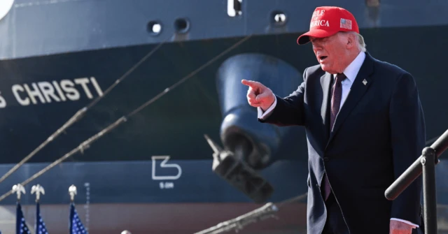 Donald Trump, con gorra roja, señala con el dedo índice al frente. 