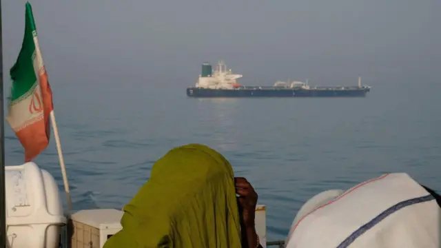 Dos mujeres miran un barco pasar por el estrecho de Ormuz